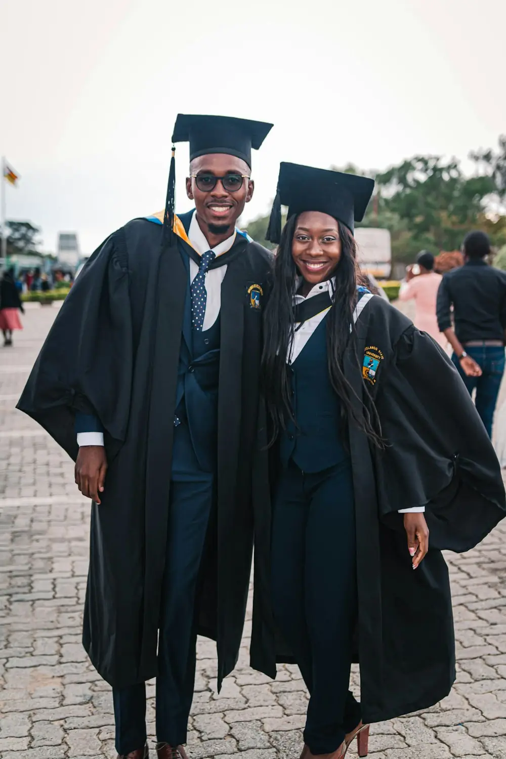 A graduate in cap and gown standing outside a university building