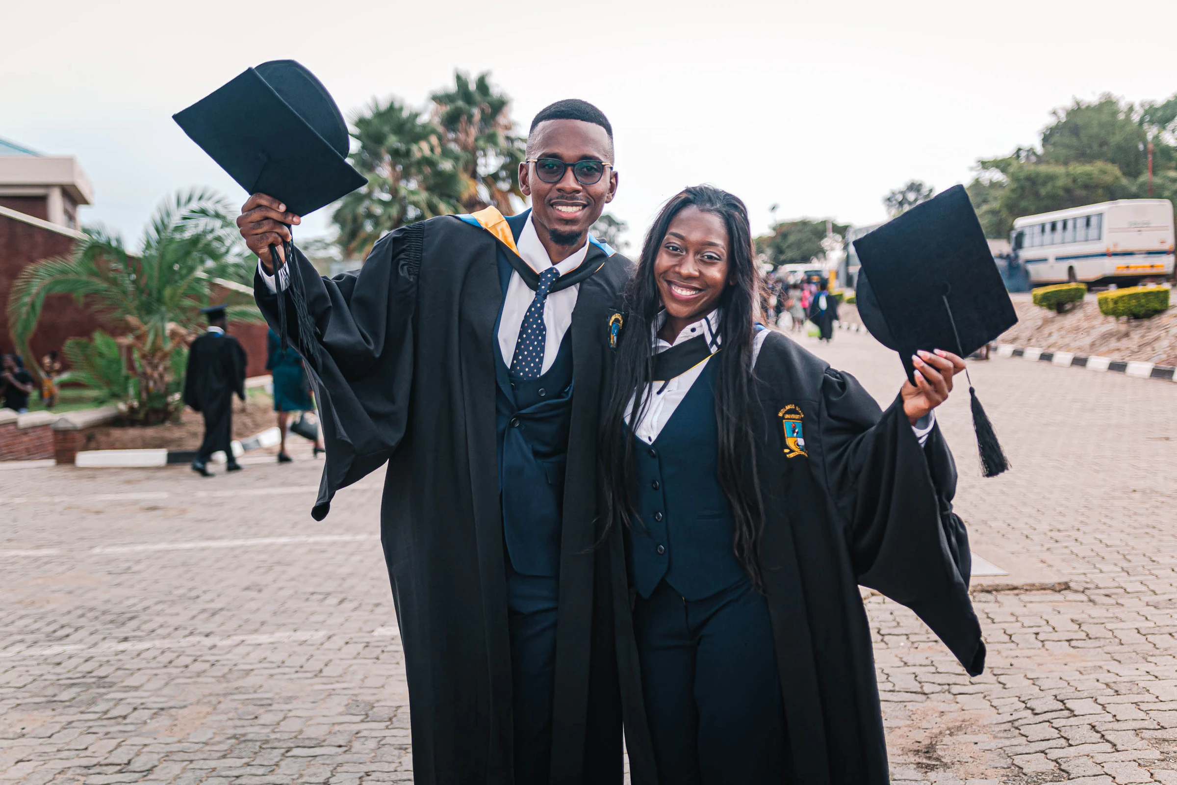 Two graduates in caps and gowns celebrating on graduation day