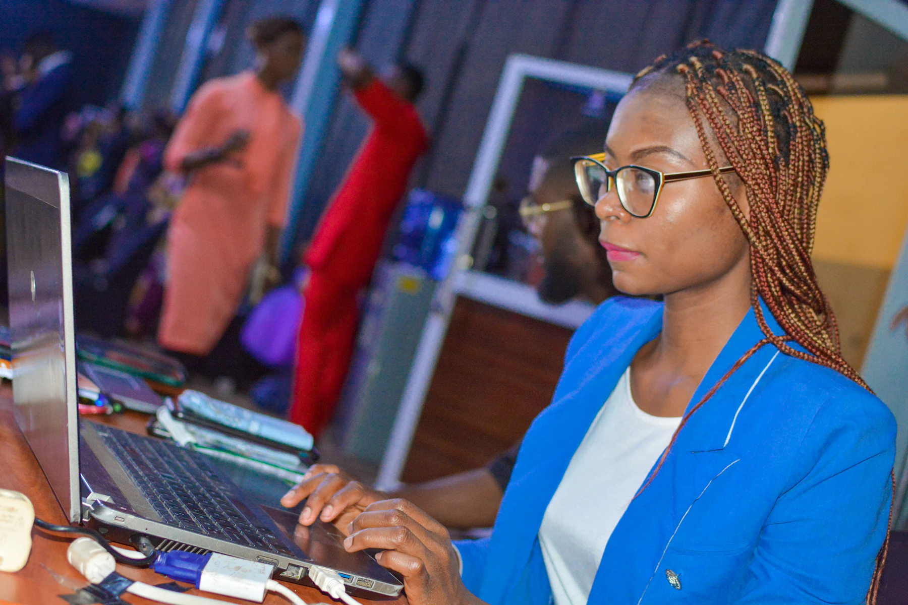 A young woman in a blue blazer working on a laptop