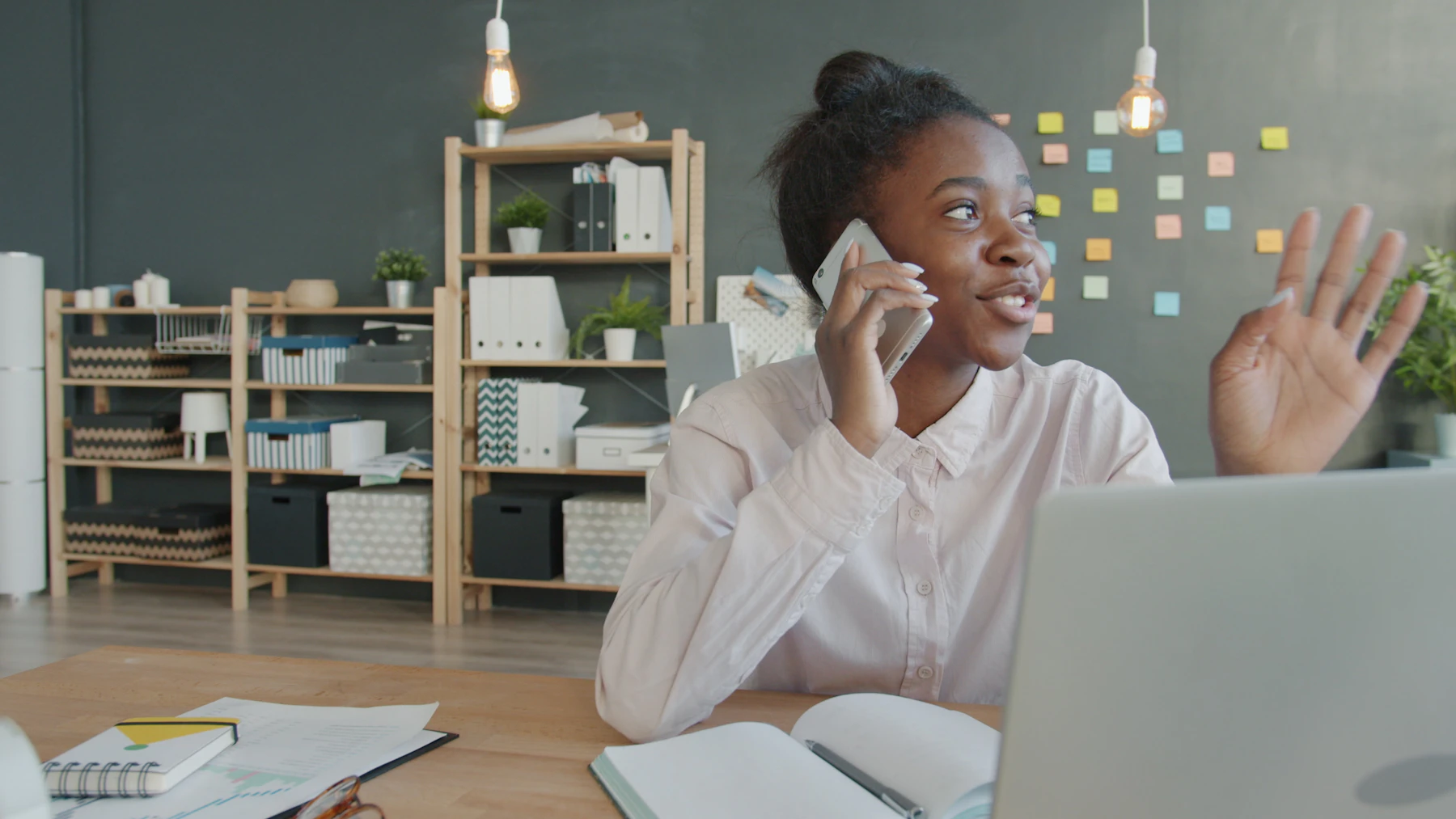 A young woman on the phone at her desk, smiling